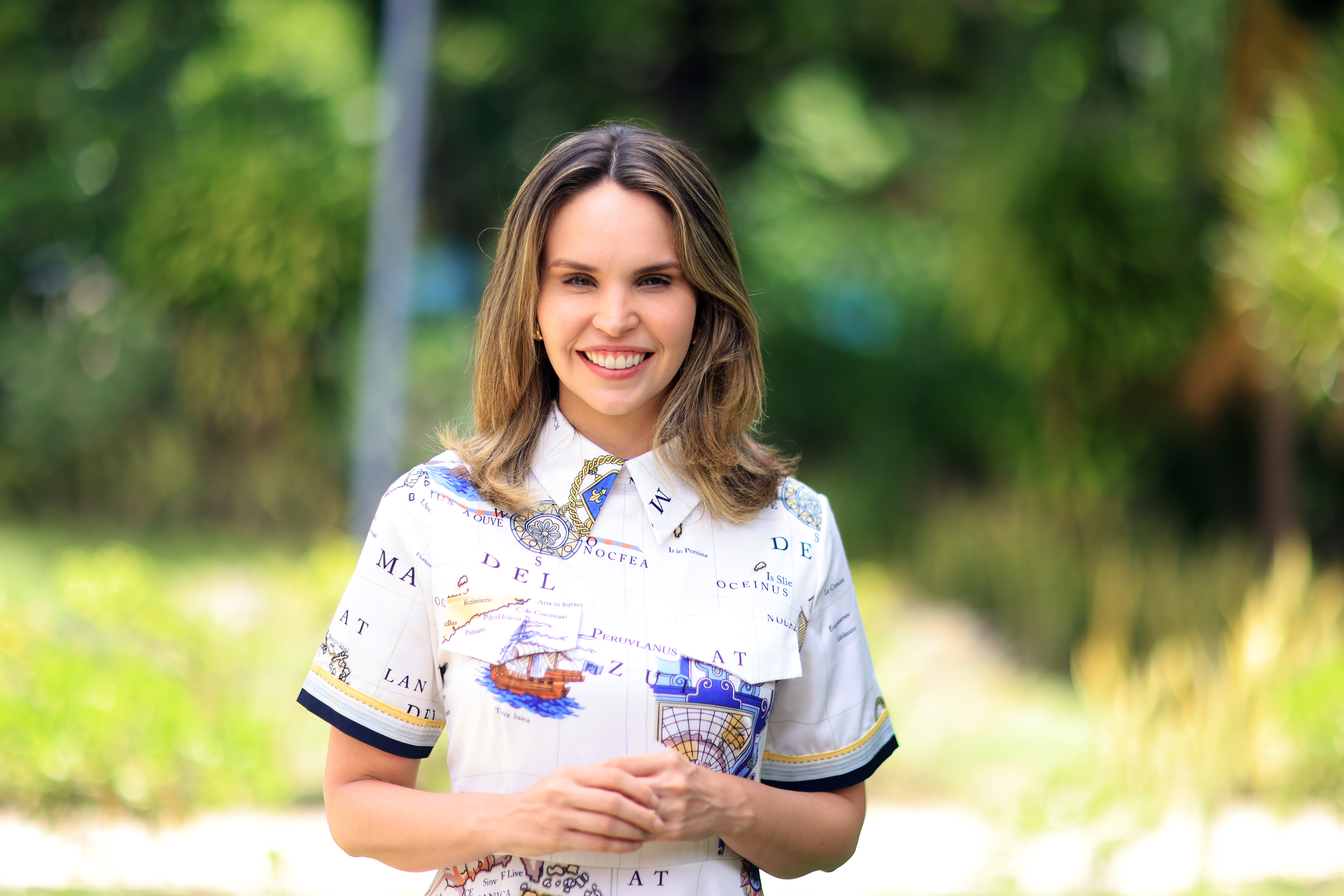 Gabriella Aguiar posa para a foto, ela está com uma blusa branca estampada